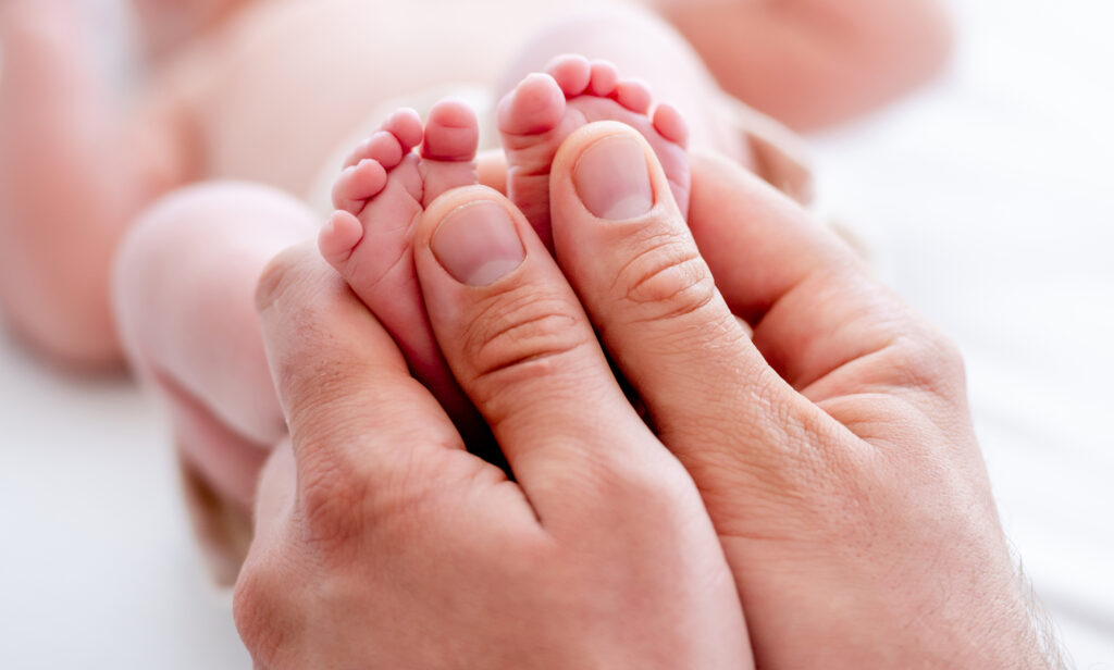 mãe segurando o pé de seu recém nascido, significando a posição da igreja católica contra o aborto