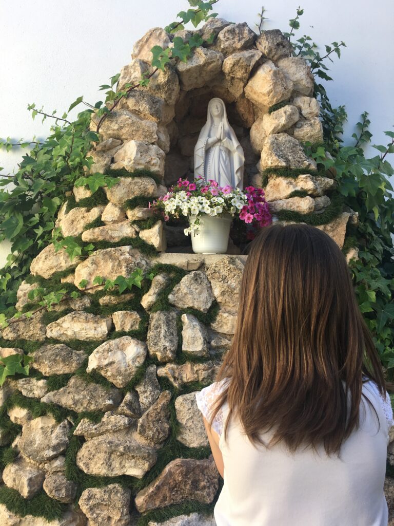 menina rezando diante da imagem de Maria, mãe de Deus e nossa mãe.