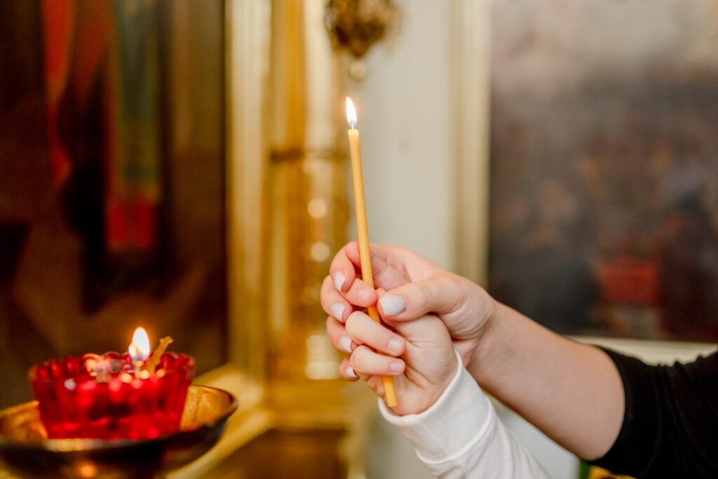mulher e criança com uma vela na mão, rezando pelas almas do purgatório, uma das obras de misericórdia.